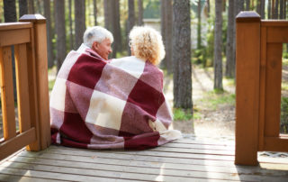 Senior couple sitting on porch with blanket
