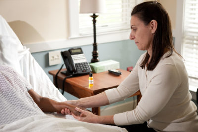 Massage therapist at bedside of patient giving massage